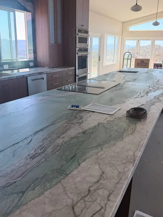 Long stone island beside built-in ovens